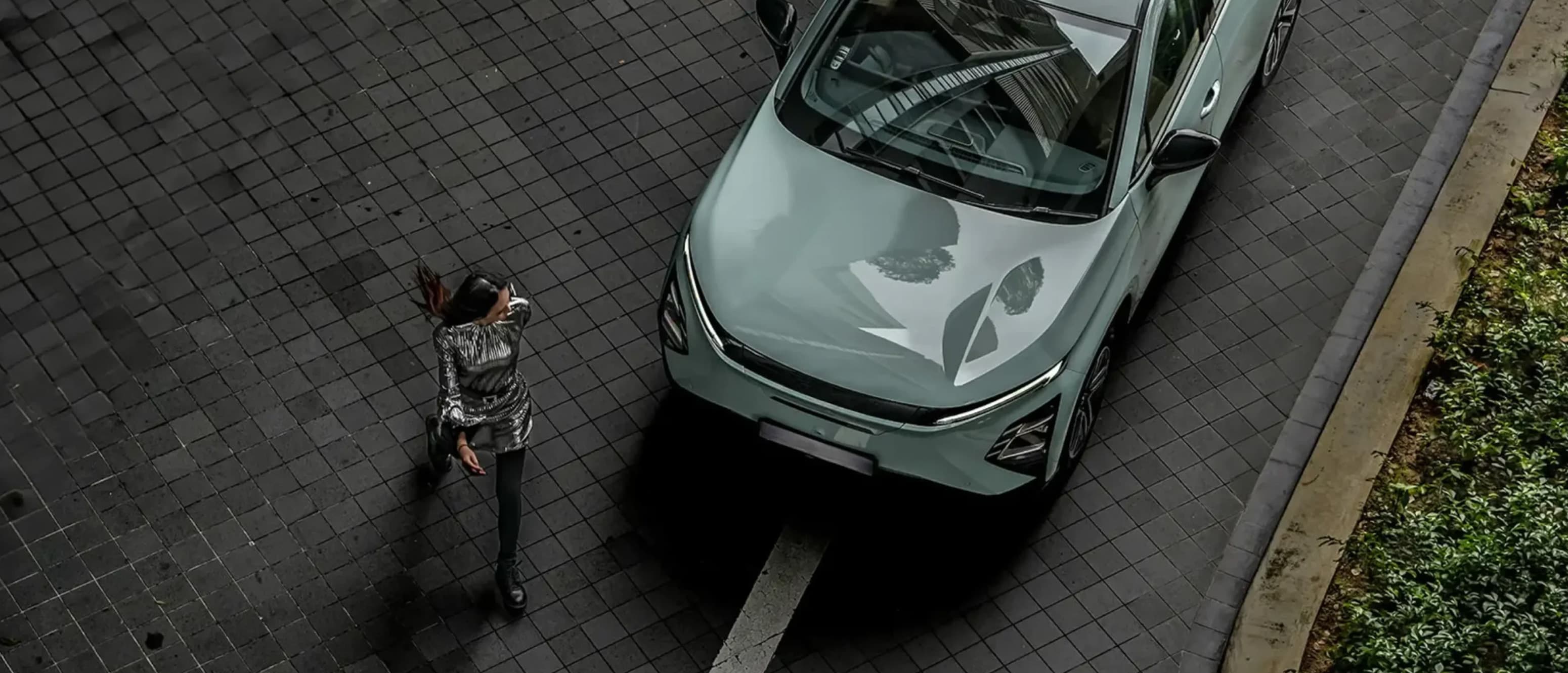 Kvinde går foran OMODA 5 EV set oppefra