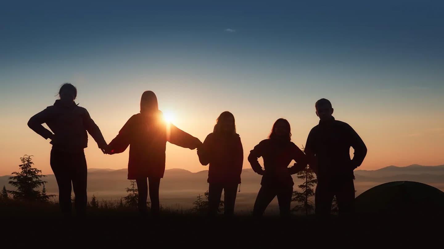 5 personer står med ryggen til og ser på solnedgang